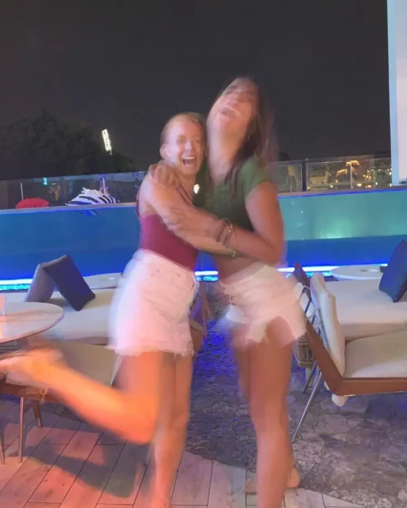 Two girls laughing and hugging for a photo at night time