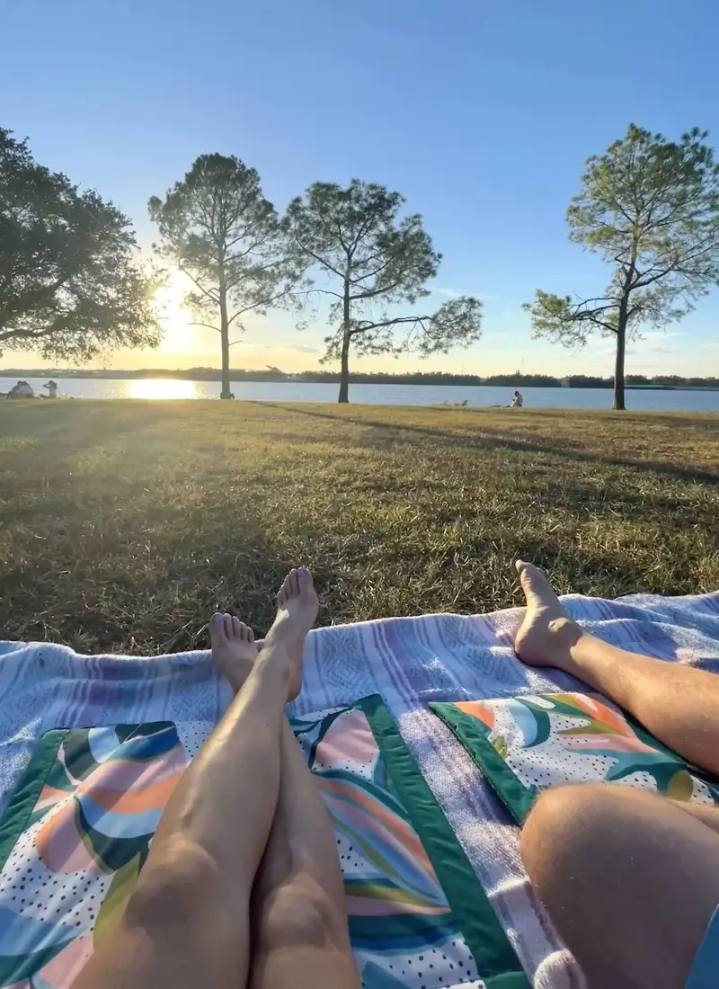 Couples legs who are sitting on a blanket looking out at the water at The Fly in Audubon Park New Orleans