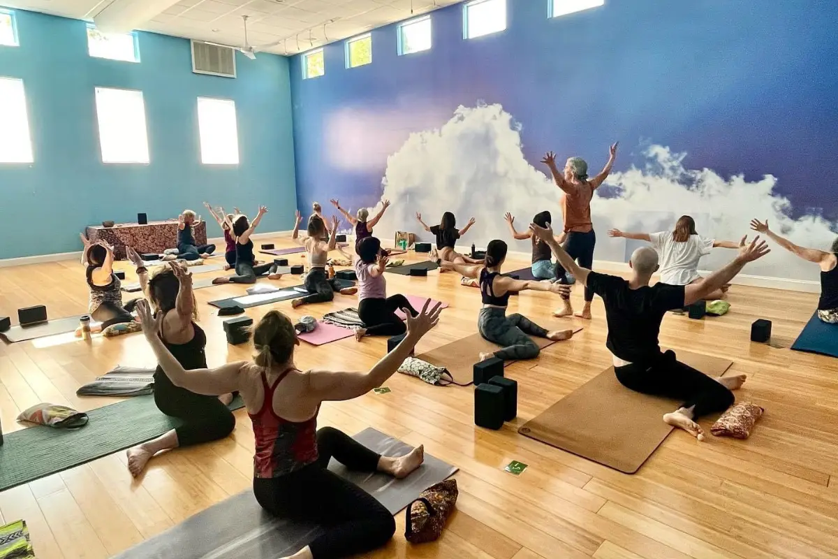 Hot yoga Asheville Yoga Center class with students raising arms
