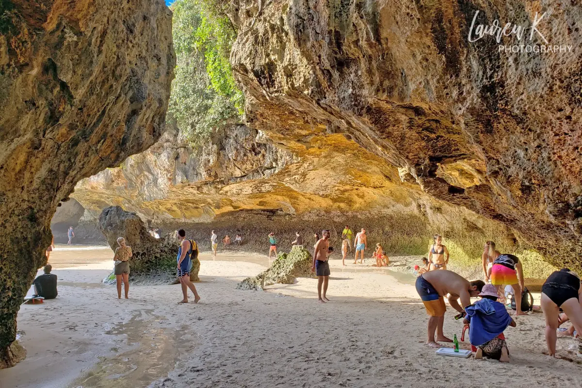 Beach entrance at Suluban Beach Uluwatu in Bali, at low tide with beach goers and surfers getting settled