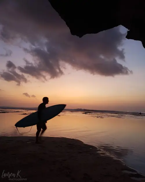 Silhouette of a surfer at sunset at Uluwatu Beach