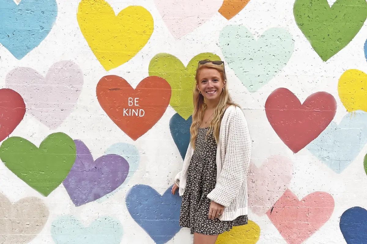 Confetti hearts mural in South End Charlotte NC. Lauren Edmondson is in the photo, who is the owner of the blog Inspired Backpacker.