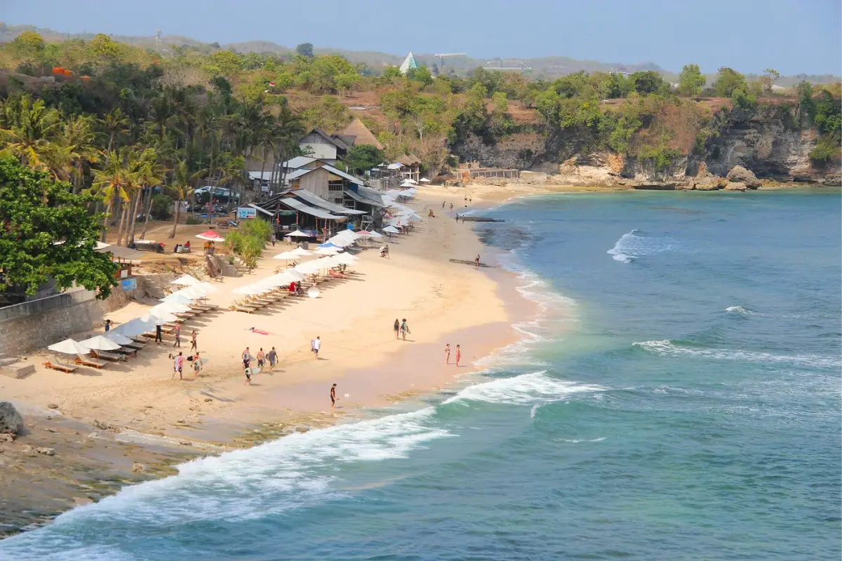 An aerial view of Balangan Beach, showing the warungs, sand, tourists and the ocean waves