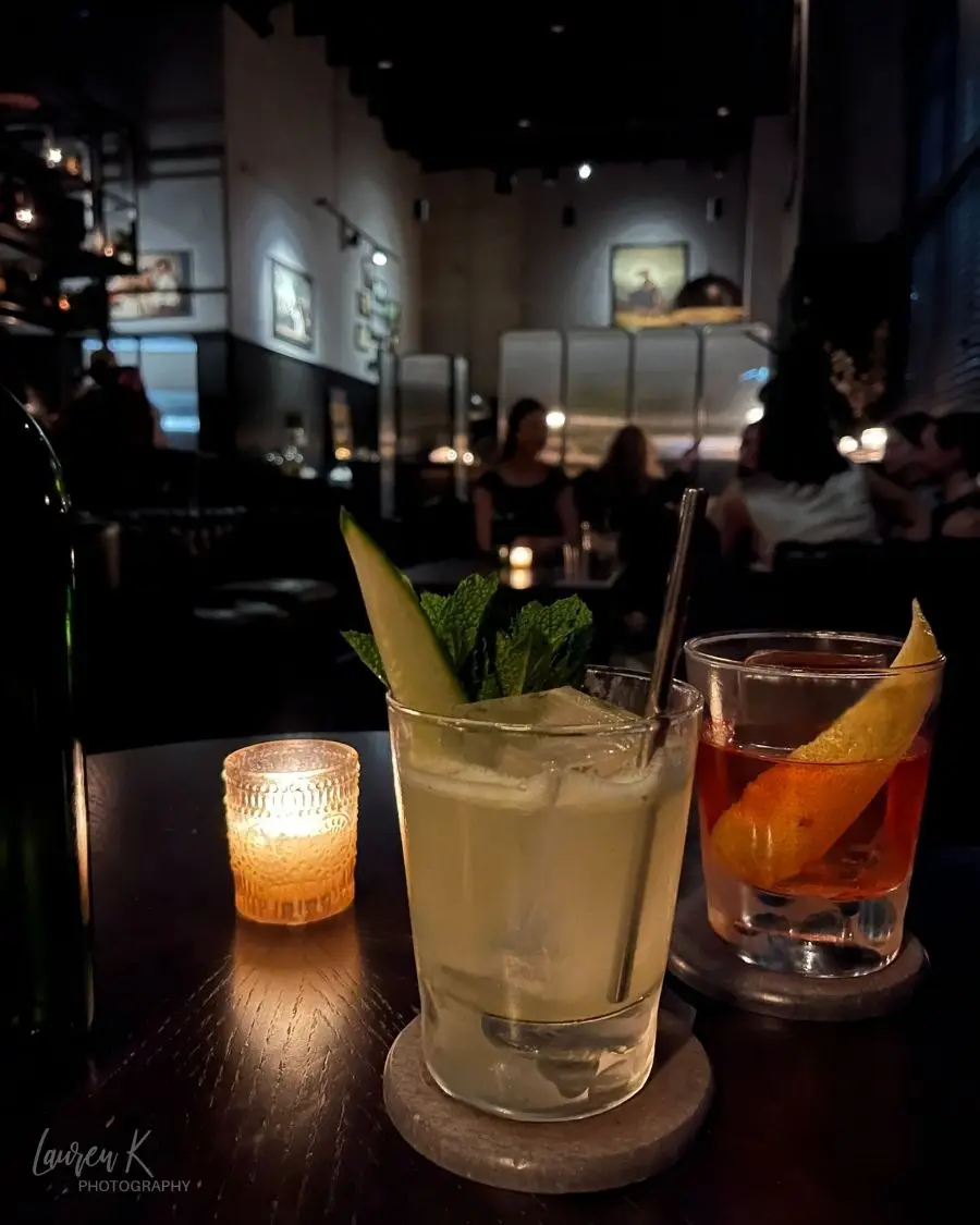 Cocktails on a dim, intimate table setting at Idlewild Charlotte, which is a no menu cocktail bar featuring a romantic atmosphere 