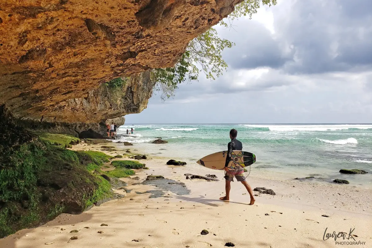 Surfer alongside a cliff at Padang Padang Beach bali on a beautiful day