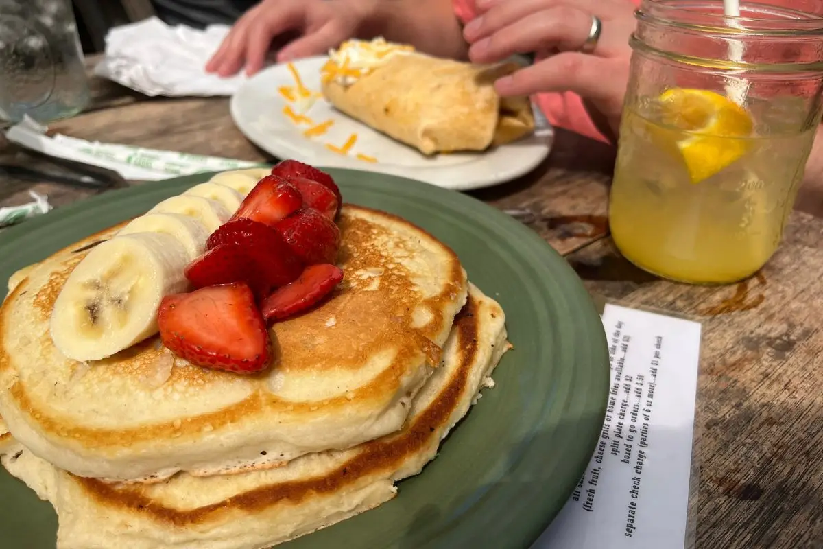 Pancakes with fresh strawberries and bananas on them, at an outdoor table at Lost Dog, which is one of the best breakfast places in Folly Beach SC