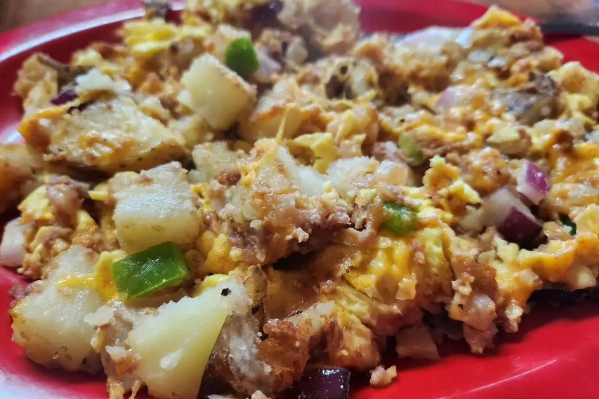 A breakfast bowl with eggs, breakfast potatoes, bacon and onions on a plate at Planet Follywood