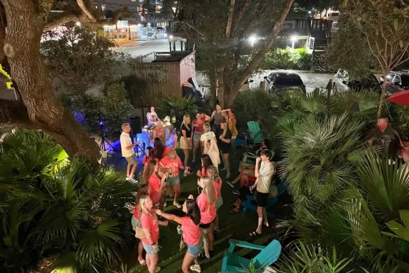A group of people dancing at Taco Boy at night surrounded by palm trees, which is one of the best bars In Folly Beach SC for DJ music on the weekends