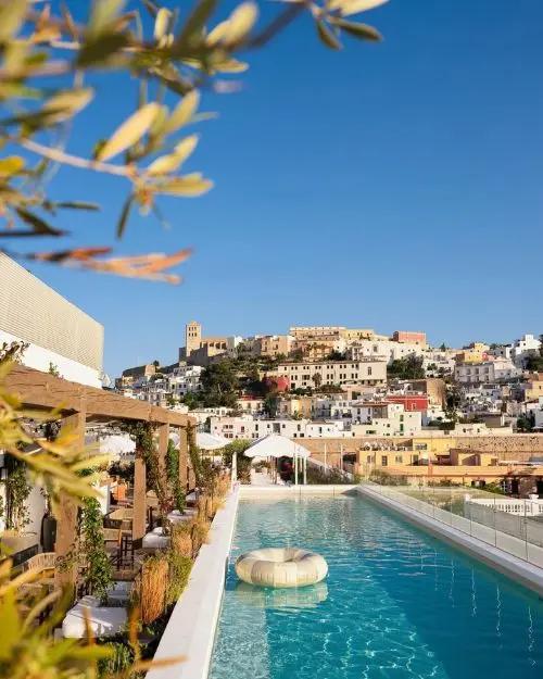 The stunning pool at one of the best Ibiza rooftop bars, under sunny skies with Dalt Vila in the background