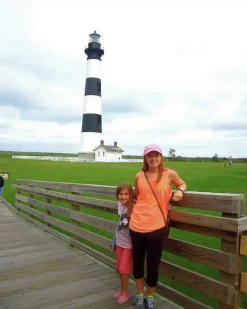 My sister and I standing on a walkway in front of the Bodie Island lighthouse