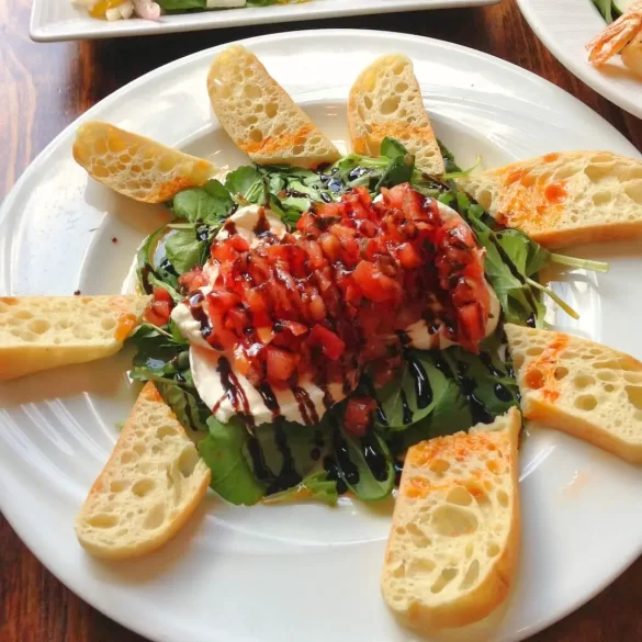 Burrata appetizer with balsamic glaze drizzled on top, fresh tomatoes and bread