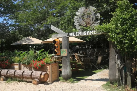 An outdoor beer garden under a canopy of trees made out of wooden carvings to blend in with the surrounding greenery 