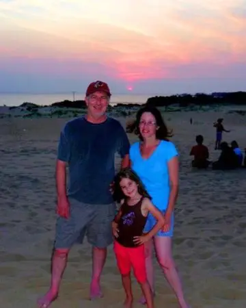 My family at Jockeys Ridge State Park posing in front of the sunset over the water behind the dunes