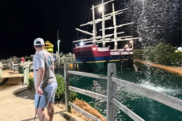 My husband looking behind him as a geyser goes off in front of the pirate ship at Mutiny Bay mini golf
