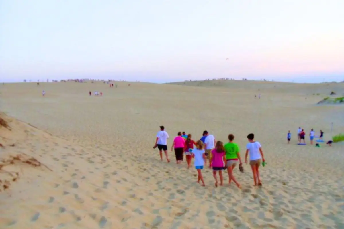 A group of people walking through the dunes at Jockeys Ridge State Park, one of the best things to do in Outer Banks NC
