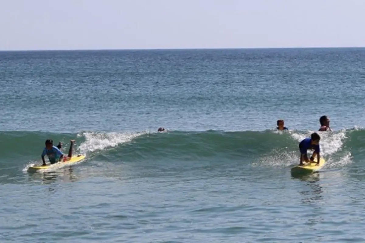 Two younger kids about to stand up on a wave, to explain that a surf lesson is one of the best things to do in Outer Banks NC especially for anyone who loves the ocean