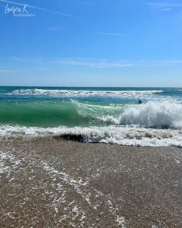 A beautiful clear green blue wave crashing on the beach at Wrightsville Beach, to show it's one of the best beaches in North Carolina