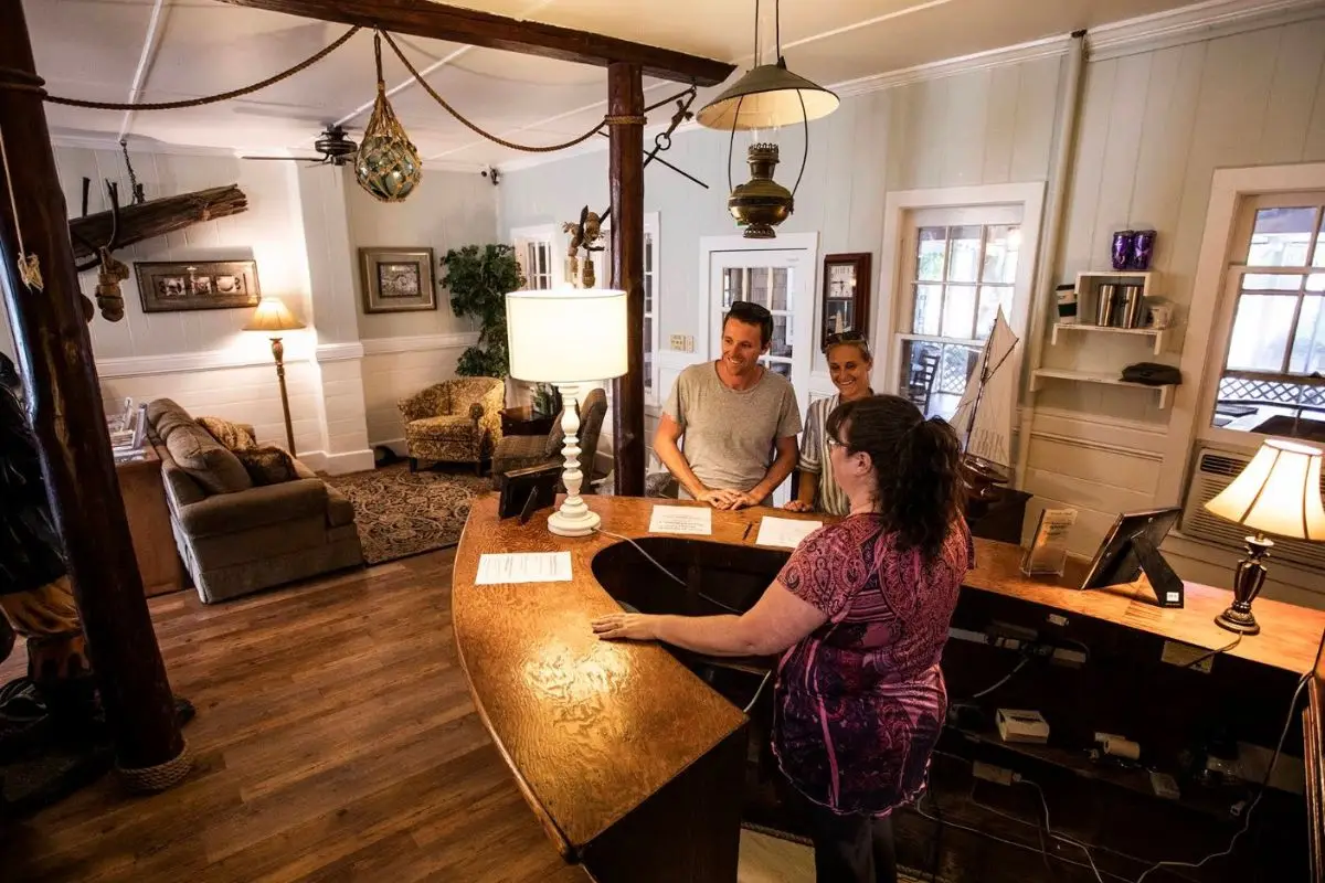 A boat shaped front desk and pirate decor in the lobby of Blackbeards Lodge, with two people checking in