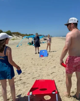 A family of four playing corn hole on the sunny beach 