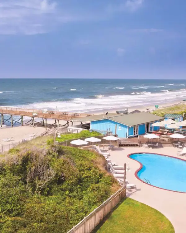 The gorgeous oceanfront pool at the DoubleTree in Atlantic Beach with the ocean waves in the background on a sunny day, to show its one of the best beaches in North Carolina