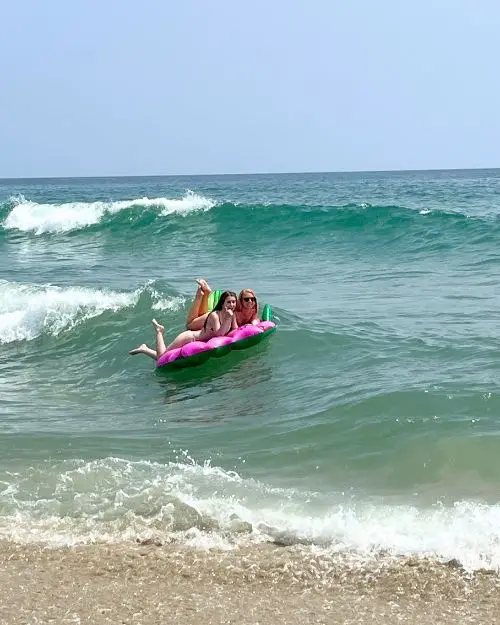 Two women on a float in the wavy ocean of the Outer Banks, one of the best beaches in North Carolina