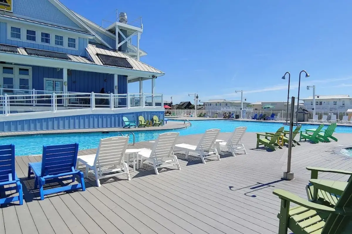 The big pool and pool house on a sunny day with lots of lounge chairs at the KOA resort