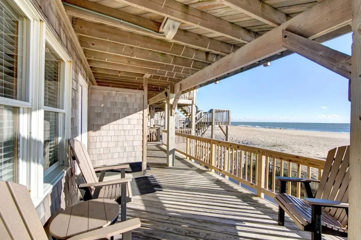 Two chairs in front of a room at the Lighthouse View Oceanfront inn, under the shade and looking out at the beach