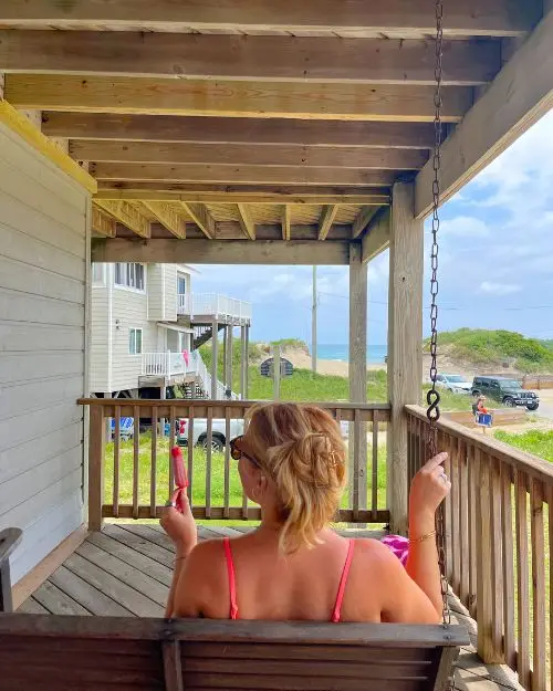 The back of me hanging out on a deck swing with a popsicle in hand in a rental home in Nags Head