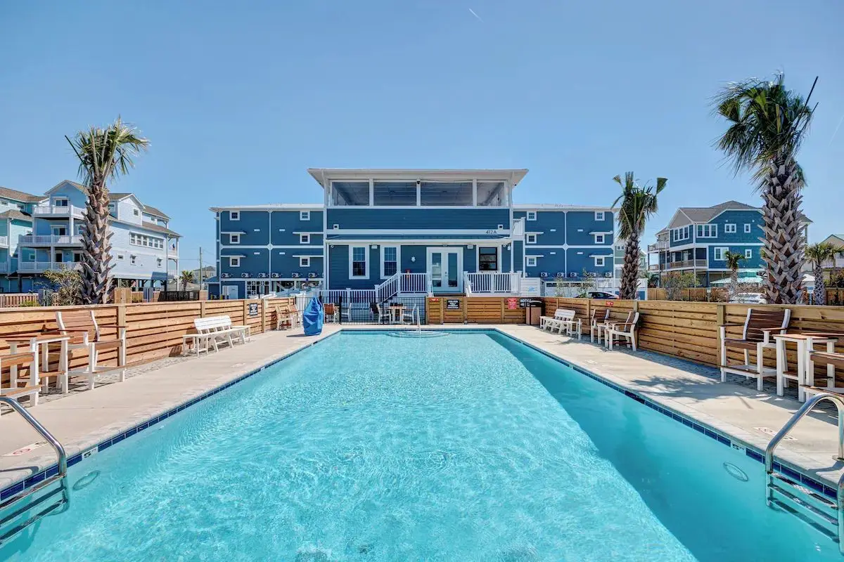 Large pool at the Saltwater Resort with the coastal designed exterior in the background under a blue sky