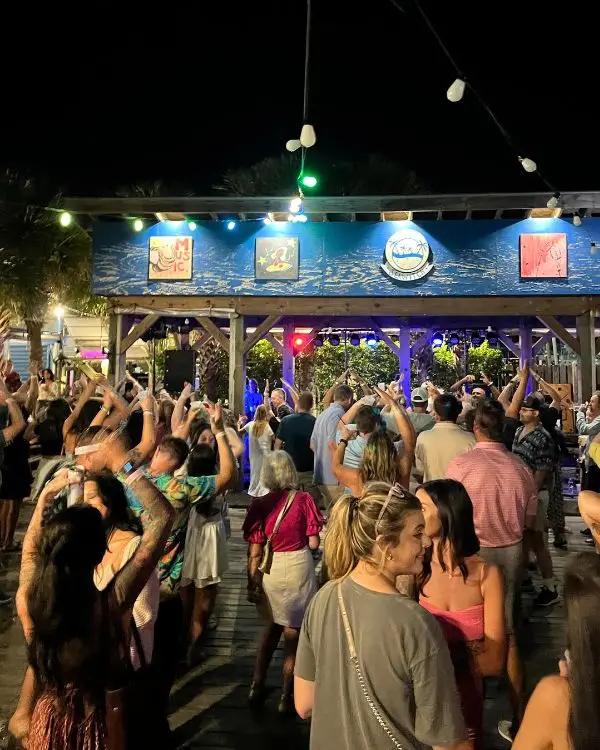 People dancing with their hands up at night time at SeaWitch bar