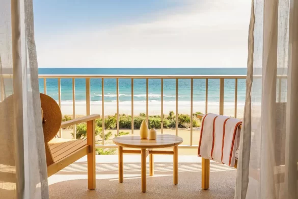 A well designed balcony chair set beyond curtains on an oceanfront balcony at Wrightsville Beach, at the trendy Trailborn Surf & Sound resort