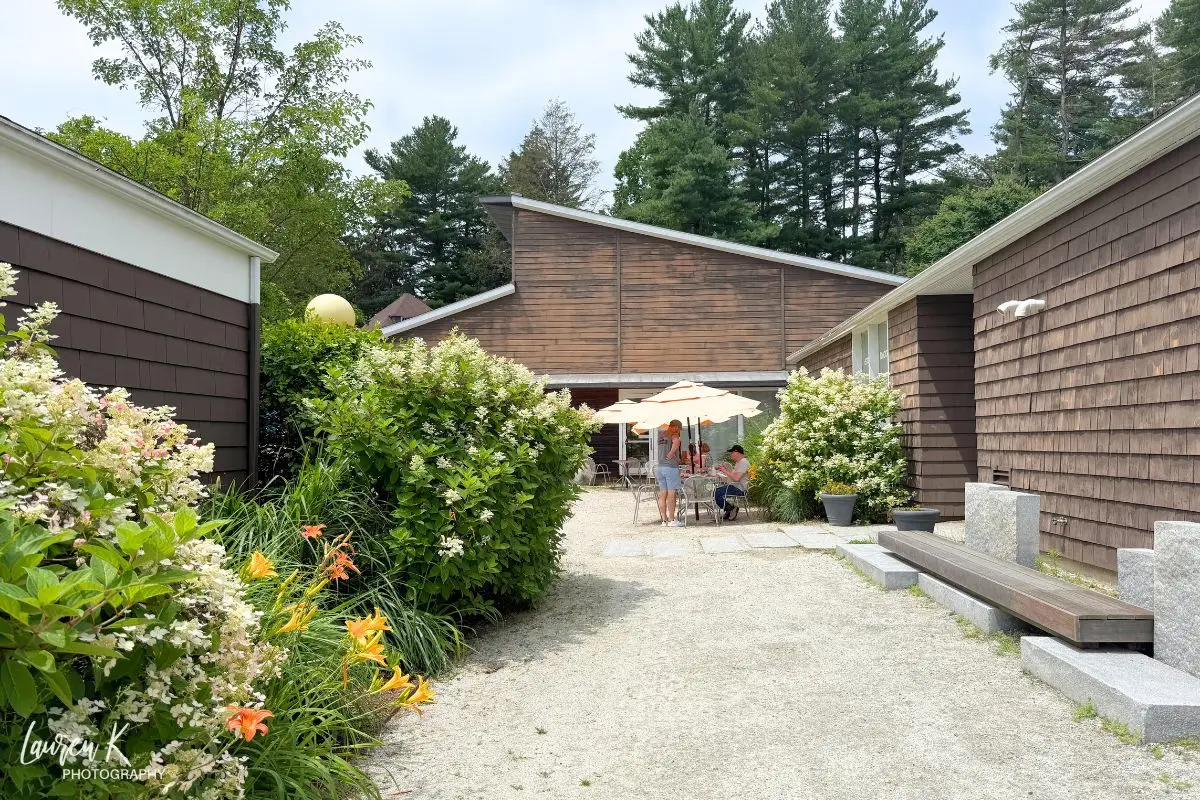 The pretty garden patio at the on site restaurant and cafe with tables that have umbrellas overhead and a few people eating