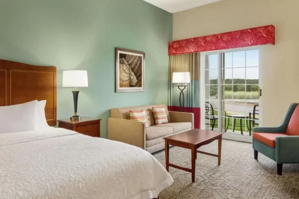 Nice hotel room with green walls and a couch and chair sitting area