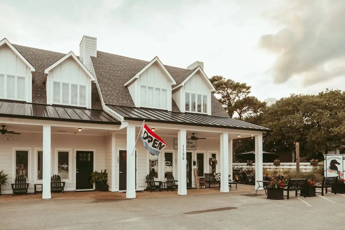 The exterior of the Wild Horse Inn with an open flag out front and cute, coastal design