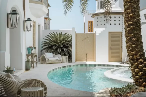 Beautiful private villa with a curved pool, two plush lounge chairs and beautiful architecture 
