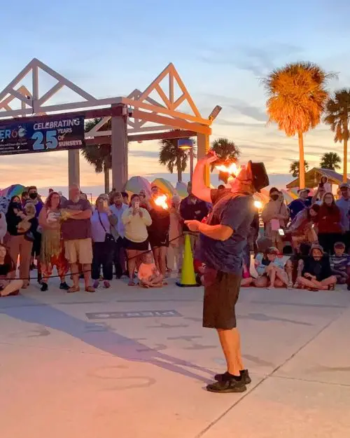 Fire entertainer surrounded by a crowd of people at sunset 