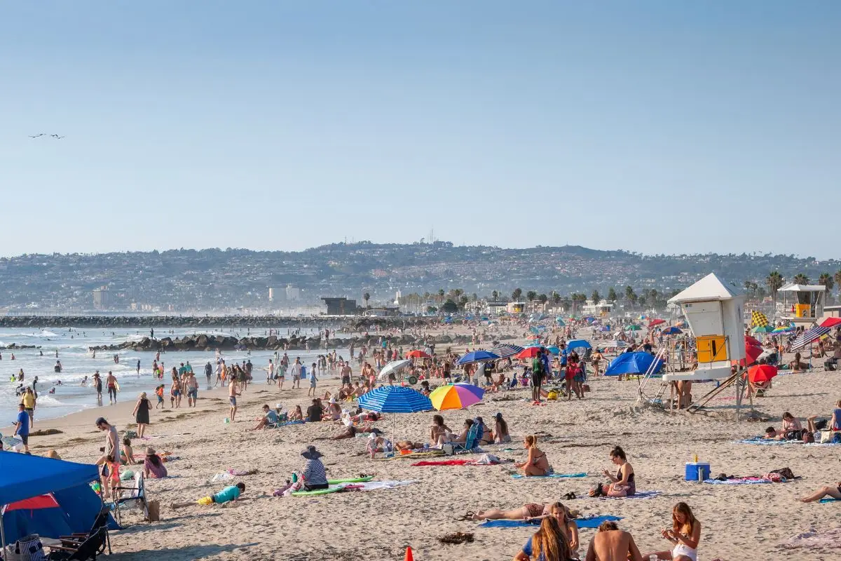 Ocean Beach dotted with people lounging, with the ocean and city in the background on a sunny evening 