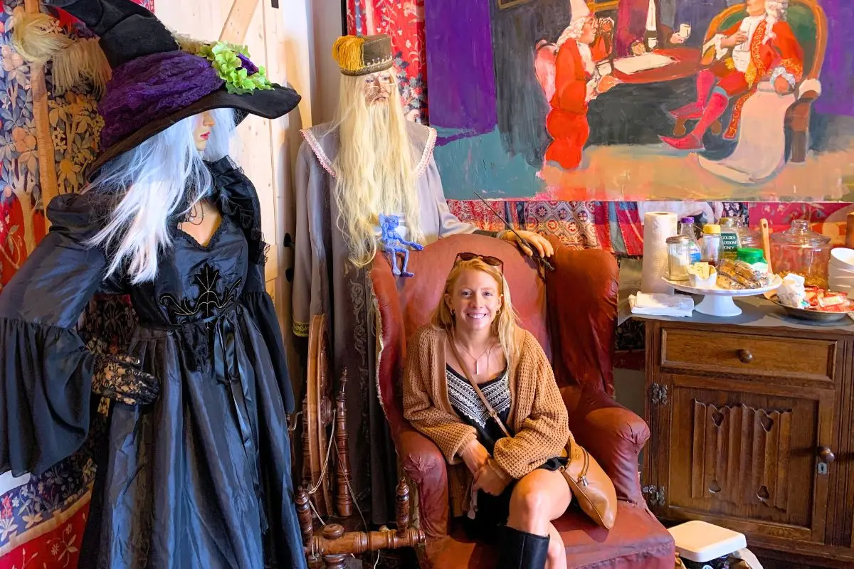 A woman in a chair sitting with witchy and Harry Potter themed props in an Airbnb in Salem