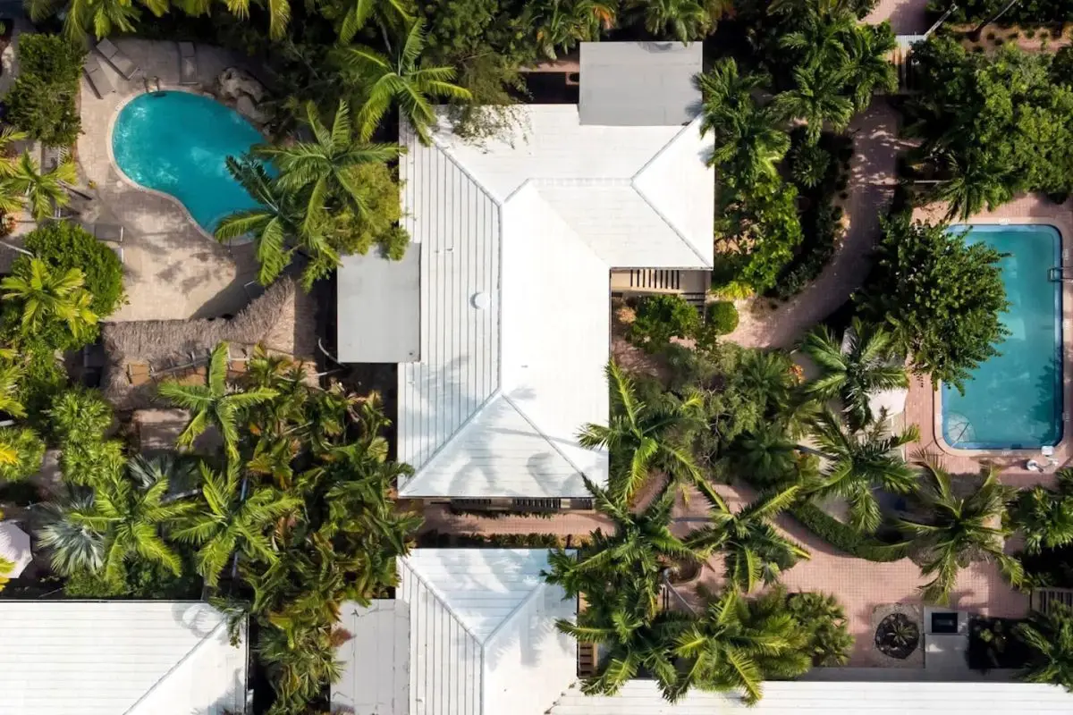 An aerial view of the Crane Beach House Boutique Hotel with lush greenery surrounding it and two pools, looking very tropical