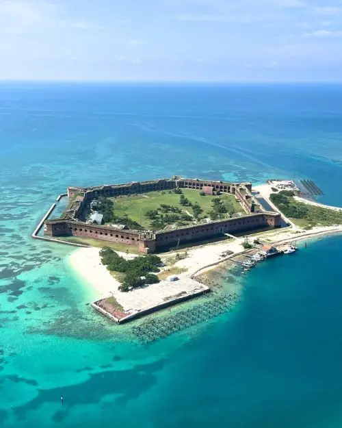 An aerial view of Dry Tortugas National Park showing the historic structure with the crystal clear ocean and sunny sky