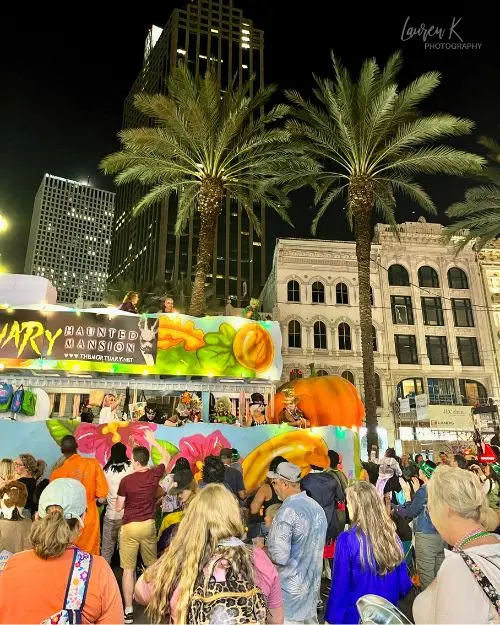 A parade float in the New Orleans Halloween parade under palm trees near the end of the route, with a crowd gathered below