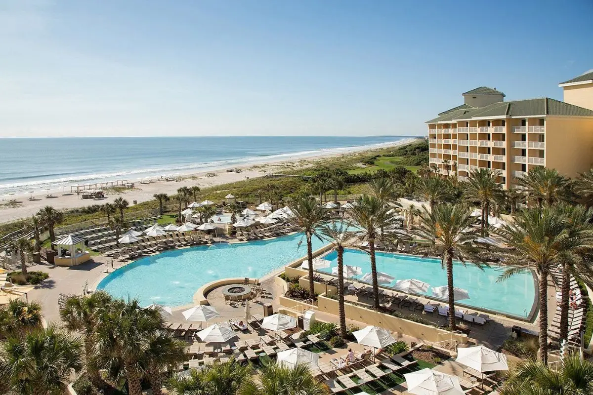 The huge pool with the ocean in the background and palm trees overhead at the upscale Omni Amelia Island
