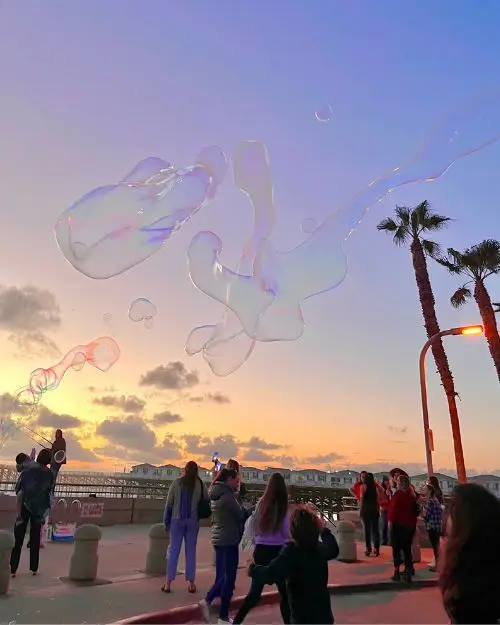 Street performers blowing giant bubbles during sunset at the Pacific Beach boardwalk