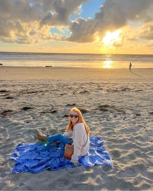 Me sitting on a towel on the beach at sunset at an empty Pacific Beach on a cool evening
