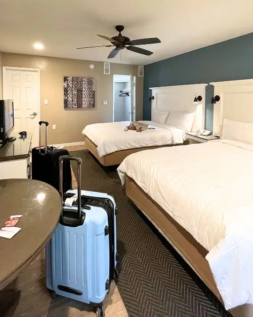 A neat and clean motel room with coastal decor and two suitcases