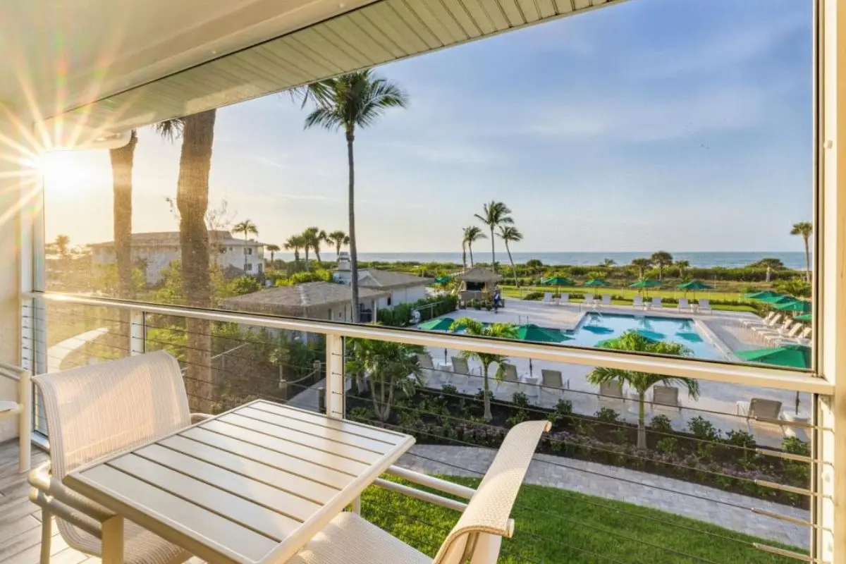 A hotel room balcony with the hotel pool and sunrise over the ocean in the background