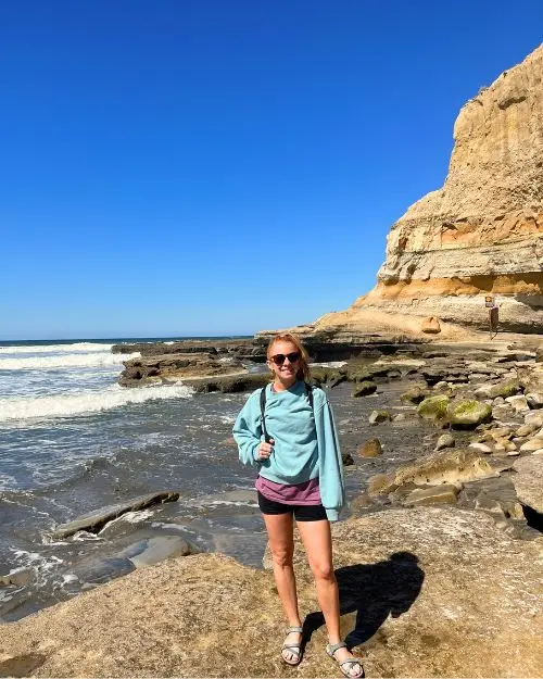 Me standing on a rock at the beach at Torrey Pines during our hike on a cloudless sunny day