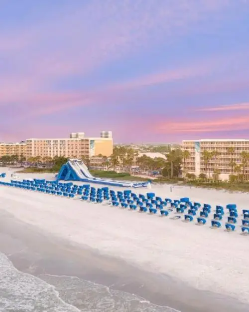 Sunset behind the Tradewinds Resort in St Pete Beach, with the giant inflatable slide on the beach along with dozens of beach chairs and cabanas