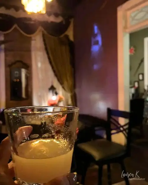 A cocktail glass in my hand and a spooky Vampire-themed bar with wall projections and other creepy decor