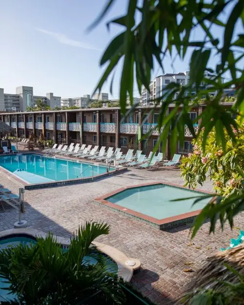 An old school tiki style hotel with two pools and palm trees